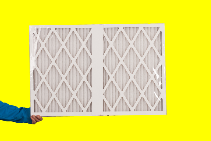 Custom sized air filter being held by hand left of image frame.